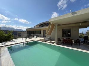a swimming pool in front of a house at Autarke Ökovilla in Agios Myronas