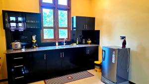 a kitchen with black cabinets and a stainless steel refrigerator at MARS Lodge home stay in Anuradhapura