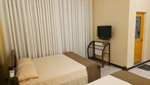 a hotel room with two beds and a television at MARS Lodge home stay in Anuradhapura