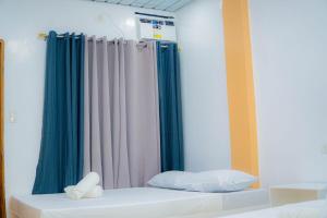 a bedroom with a bed with blue and white curtains at Quartz Suites in Camiguin
