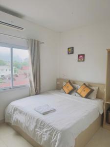 a bedroom with a large white bed with a window at Vang Vieng Ha Ha Hotel in Vang Vieng