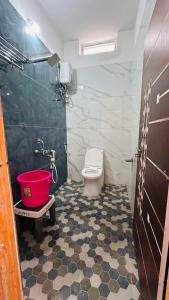 a bathroom with a toilet and a bucket in it at Siddhartha homevibes hampi in Hampi