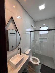 a bathroom with a sink and a toilet and a mirror at Casa completa com wifi, garagem, próximo ao centro in Piatã