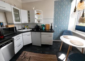 a small kitchen with white cabinets and a table at Apartmenthaus am See - Seeblick Suite - Nähe Motorsportarena in Seehausen