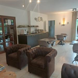 a living room with two couches and a kitchen at B&B Madoli in Érezée