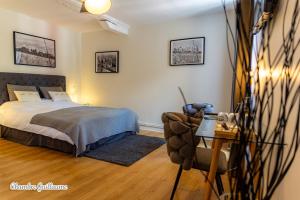 a bedroom with a bed and a chair and a table at La Maison Des Buis in Falaise