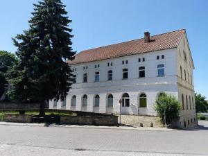 a large white building with a tree in front of it at Apartmenthaus am See - Seeblick Suite - Nähe Motorsportarena in Seehausen