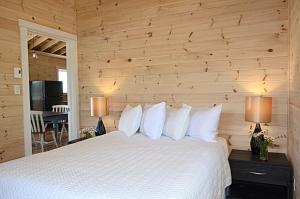 a bedroom with a white bed with wooden walls at Still Point Lodge in Deep Brook