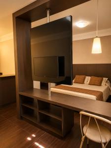a bedroom with a bed and a desk with a television at Palace Hotel in Itajubá