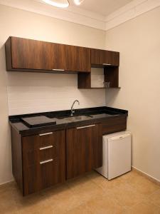 a kitchen with wooden cabinets and a sink and a refrigerator at Palace Hotel in Itajubá +14 photos