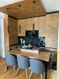 a kitchen with a wooden table and blue chairs at Lux Apartman Leša in Vrdnik