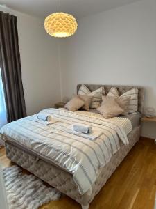 a large bed in a bedroom with a chandelier at Lux Apartman Leša in Vrdnik