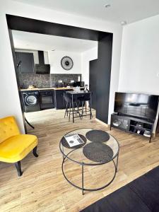a living room with a table and a yellow chair at Suite Arum classée 3 étoiles avec balnéo in Roanne