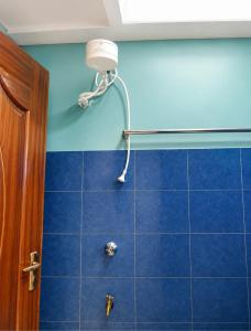 a shower in a bathroom with blue tiles at Nexus Staycations in Maralal