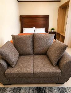 a couch with pillows in a bedroom with a bed at Nexus Staycations in Maralal