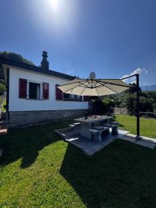 ein Picknicktisch mit Sonnenschirm vor einem Haus in der Unterkunft Casa Prisca in Bellinzona