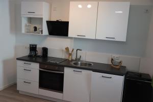 a kitchen with white cabinets and a sink at Ferienoase übern Zottbachtal in Pleystein +9 photos