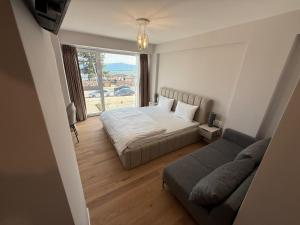 a bedroom with a bed and a couch and a window at Struga Lake Suites in Struga