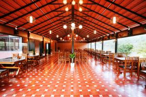 a dining hall with tables and chairs and lights at Apoorva River Resort in Māvingundi