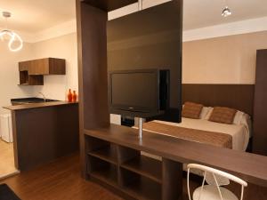 a bedroom with a bed and a desk with a television at Palace Hotel in Itajubá