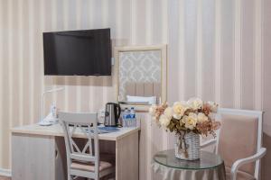 a room with a desk with a vase of flowers on a table at Hotel Dream Land Tashkent in Tashkent