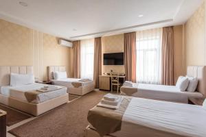 a hotel room with three beds and a desk at Hotel Dream Land Tashkent in Tashkent