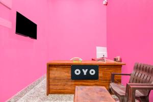 a pink wall with a desk with a sign that says oxy at Hotel O Elegant Stay CDA in Cuttack