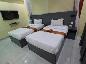 two twin beds in a room with a tv at The alder hotel and accommodation in Bungoma