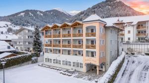 a hotel in the snow with mountains in the background at Residence Diana Apartment 303 in Terento