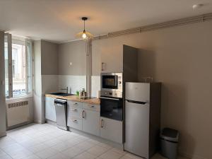 a kitchen with a refrigerator and a microwave at Appartement centre-ville Montluel in Montluel