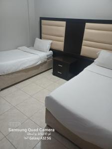a room with two beds and a nightstand between them at فندق نوارة المنسك in Abha +7 photos