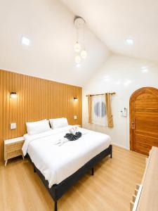 a bedroom with a large white bed with a wooden wall at บ้านต้นจันทร์ in Nathon Bay