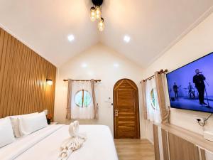 a bedroom with a bed and a tv on the wall at บ้านต้นจันทร์ in Nathon Bay