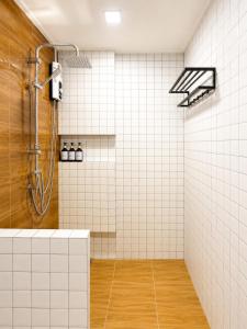 a bathroom with a shower with white tiles at บ้านต้นจันทร์ in Nathon Bay