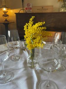 a table with wine glasses and a vase with yellow flowers at Hotel Ristorante San Michele in Ome