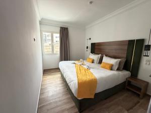 a hotel room with a large bed with orange pillows at Hamilton Suites & Appart in Casablanca