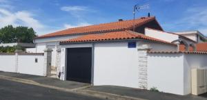 a white house with a gate and a red roof at Les Belous in La Rochelle