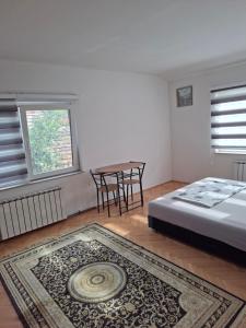 a bedroom with a bed and a table and a rug at Apartman Mickey in Sarajevo