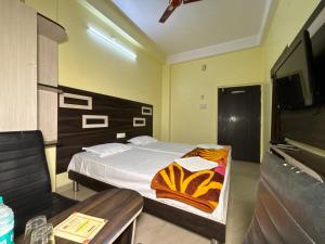 a bedroom with a bed and a table and a television at Hotel Radiation Deoghar in Deoghar