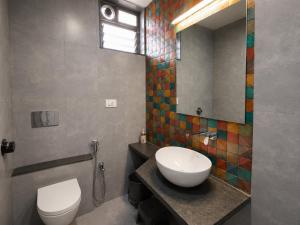 a bathroom with a toilet and a sink and a mirror at Hotel Fountain - Kamrej in Surat +21 photos