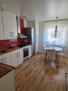 a kitchen with white cabinets and a table and a dining room at Central lägenhet i Visby -4 person inkl parkering in VBY