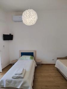 a white room with a bed and a chandelier at A Chera Via in Laureana Cilento