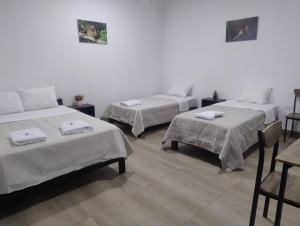 three beds in a room with white walls at BACHÍG Hospedaje in Moyobamba