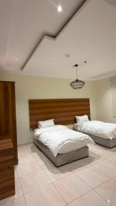 a bedroom with two beds and a chandelier at فيولورين سويتس in Al Baha +3 photos