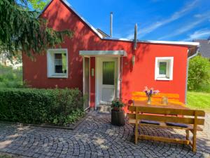 a red house with a bench in front of it at Antonios Hüttenzauber in Oberhof