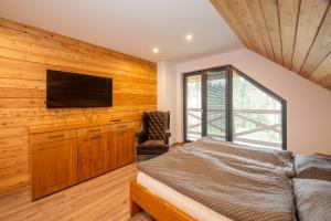 a bedroom with a bed and a flat screen tv at Chata Alexia Oravice in Vitanová