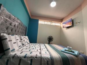 a bedroom with a bed and a tv on the wall at Hostal Muchik in Chiclayo