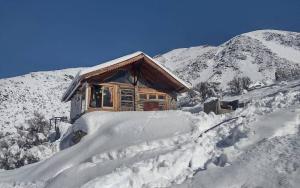 a cabin on a snowy mountain with a pile of snow at Cabaña Vallecitos in Ciudad Lujan de Cuyo