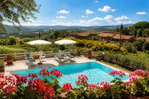 a pool in a garden with flowers and umbrellas at Villa Vale in Casole dʼElsa