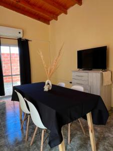 a dining room with a table with chairs and a television at Altos del Pissis I in Tinogasta